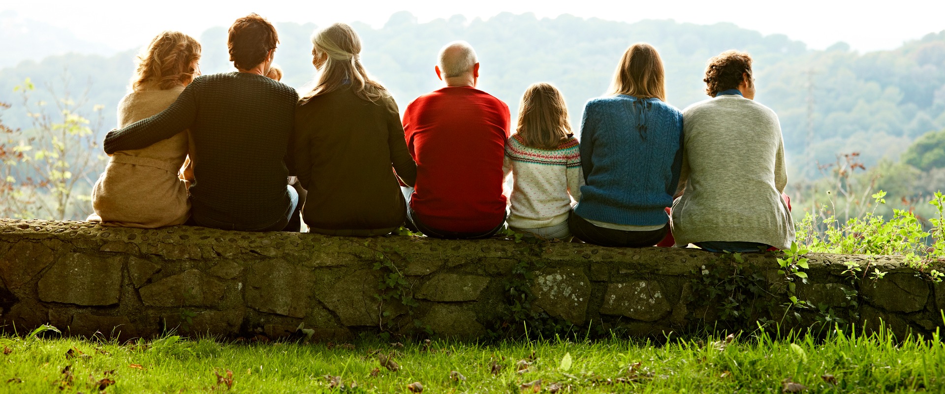 Multi-generational family sitting on stone wall